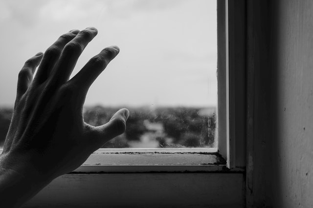 black and white image of a hand reaching out to a window